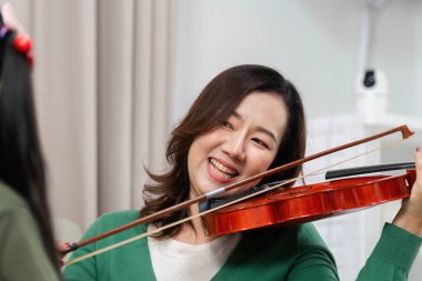 Gülümseyen bir anne kızına eğlenceli bir müzik dersi verir, ona keman çalmayı öğretir, aile bağlarını ön plana çıkarır..