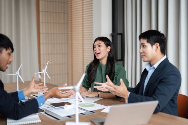 Çeşitli bir ekip, bir şirket ortamında ESG stratejileri ve sürdürülebilir uygulamalar hakkında canlı bir tartışmaya girişir..