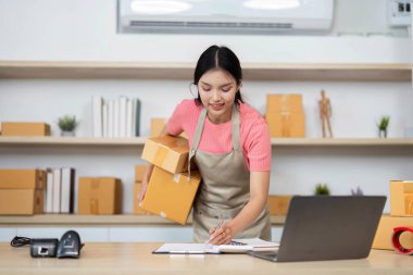 Kendini işine adamış bir girişimci kutuları paketlerken siparişleri yazar ve küçük işletme operasyonlarının özünü anlatır..