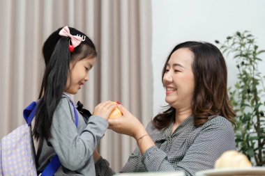 Bir anne sevgi dolu bir şekilde kızına hamur işi uzatır. Sıcak bir evde tatlı bağlarını ve neşeli anlarını vurgular..