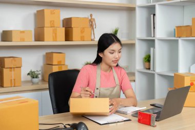 Odaklanmış bir girişimci, onun küçük işletme çalışma alanında paketler ve notlar düzenler, verimlilik ve adanmışlık sergiler.