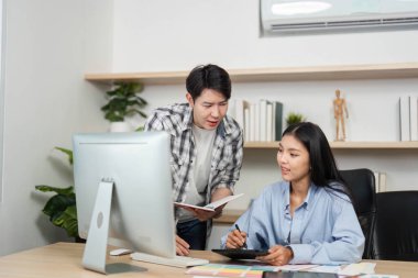 Çağdaş bir ofis ortamında UX ve UI tasarımı, fikir ve renk seçimlerinde işbirliği yapan iki genç profesyonel.