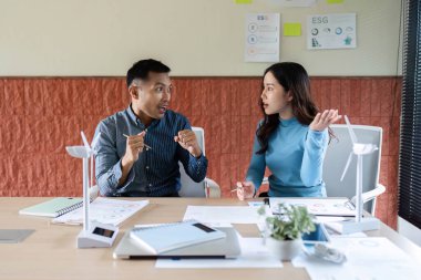 İki meslektaş, ESG stratejilerini, belgeleri incelemeyi ve parlak bir ofis ortamında görüşleri paylaşmayı animasyonlu bir şekilde tartışıyor..