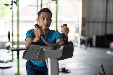 Eliptik bir makine kullanarak spor yapmaya odaklanan bir adam kendini forma ve sağlıklı yaşama adamıştır..