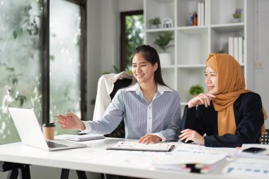 İki kadın, ortak bir ofis alanında strateji ve mali raporları tartışan bir dizüstü bilgisayardaki verileri analiz ediyor..