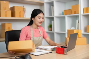 Girişimci, küçük işletme lojistiğini verimli bir şekilde yönetirken, aynı zamanda ev ofis ortamındaki paketlerle de ilgilenir..