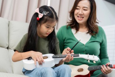 Bir anne ve kızı birlikte müziği keşfederken, ukulele dersleri yoluyla yaratıcılığı ve bağlantıyı teşvik ederken neşeli bir an..