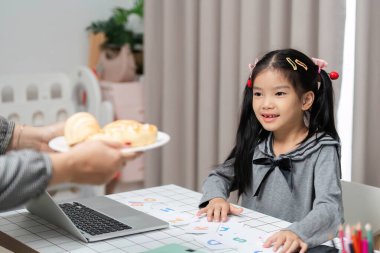 Genç bir kız masasında mektuplarla ve öğrenme materyalleriyle mutlu bir şekilde etkileşime geçerek, olumlu bir öğrenme ortamı yaratıyor..