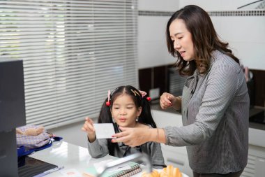 Bir anne kızına öğrenim faaliyetlerinde rehberlik eder, neşe ve pastalarla dolu destekleyici bir ortam sağlar..