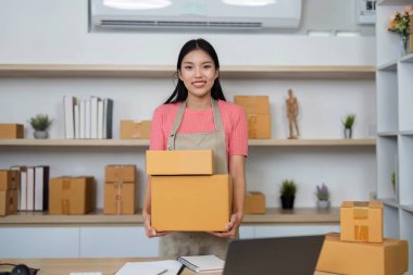 Genç bir girişimci, küçük işletmesinin günlük faaliyetlerini ön plana çıkaran paketlerini ev ofisinde sergiliyor..