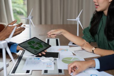 Profesyonel bir ekip, strateji toplantısı sırasında tablet üzerindeki verileri analiz ederken ESG girişimlerini tartışıyor.
