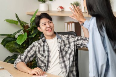 Neşeli bir tasarımcı, üretken bir UX ve UI tasarım toplantısı sırasında bir meslektaşıyla beşlik çakarak takım çalışmasını teşvik eder..