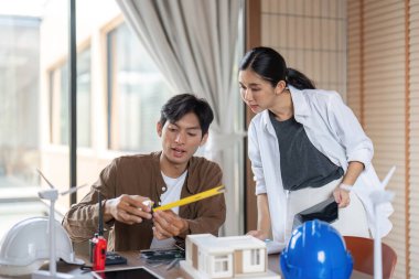 İki genç profesyonel, bir modeli incelerken sürdürülebilir mimari ve ESG uygulamaları hakkında bir tartışmaya girişti.