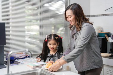 Bir anne ve kızı, yemek hazırlamak için birlikte çalışırlar. Parlak bir mutfakta takım çalışmasını ve iletişimi teşvik ederler..