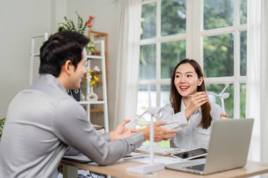 İki profesyonel, yenilenebilir enerji çözümleri konulu bir istişarede bulunarak, parlak bir ofis ortamında ESG stratejilerine odaklanıyor.