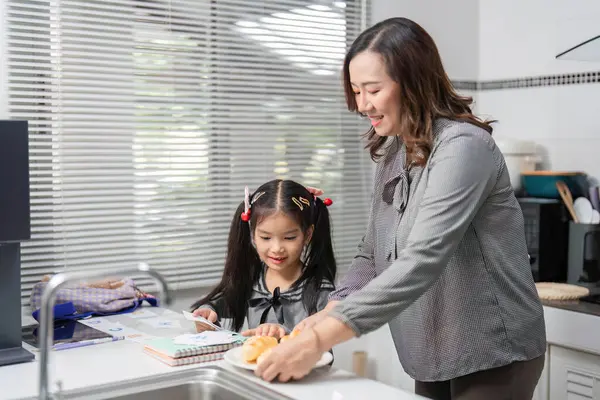 Bir anne ve kızı, yemek hazırlamak için birlikte çalışırlar. Parlak bir mutfakta takım çalışmasını ve iletişimi teşvik ederler..