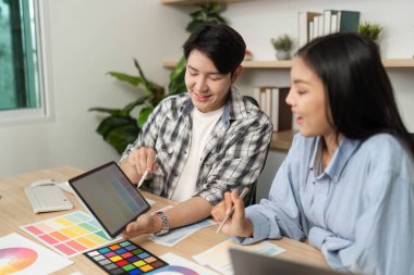 İki tasarımcı, UX ve UI tasarım fikirlerini bir tablet üzerinde tartışıp sergileyerek, işbirliği çabalarını arttırıyorlar..