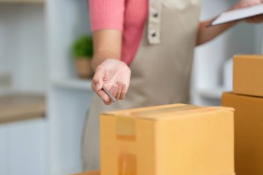 Teslimat için paketler hazırlayan bir girişimci küçük işletmelerinde verimlilik sergiliyor..