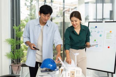 Genç bir ekip, modern bir çalışma alanında ESG ilkelerine ve sürdürülebilirliğe odaklanan bir mimari model üzerinde işbirliği yapıyor..