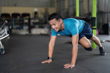 Bir adam, modern bir spor salonunda güç ve bağlılık göstererek şınav çeker..