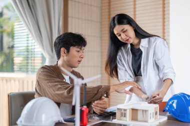 Genç bir mimar ve mühendis, ESG ilkeleri ve yenilikçi tasarımı vurgulayarak sürdürülebilir bir yapı modeli üzerinde işbirliği yapmaktadır..