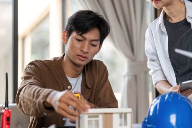 İki mimar, çalışmalarında ESG ilkelerini vurgulayarak bir model ve çevre dostu bir inşaat projesinin planlarını tartışıyor..