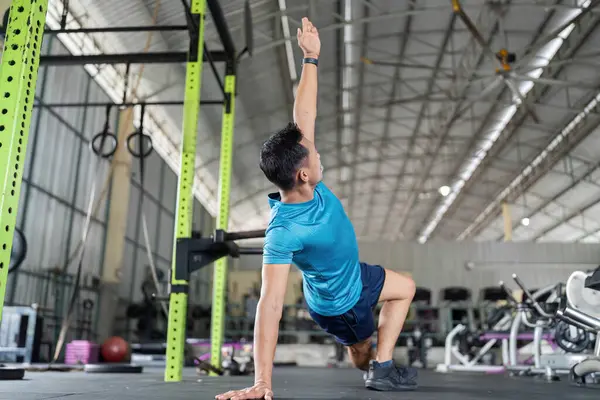 Bir erkek atlet, fitness ortamında hareket kabiliyetini ve çekirdek dayanıklılığını artırmak için yan kalaslar kullanır..