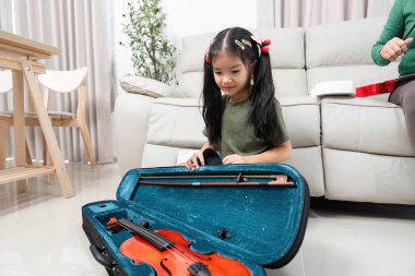 Genç bir kız hevesle keman kutusunu açar, ilk müzik dersine hazırlanır, bir ev ortamında coşku ve merak gösterir..