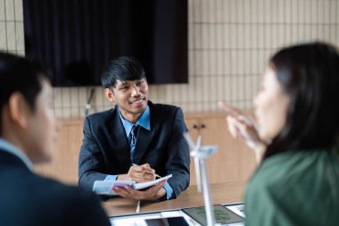 Profesyonel bir ekip ESG girişimlerinde işbirliği yaparak, parlak bir ofiste sürdürülebilirlik ve etik yönetim stratejilerini tartışıyor.