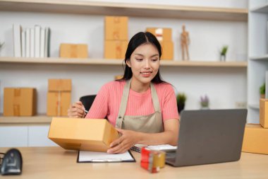 Bir girişimci, küçük bir iş ortamının dinamiklerini gösteren kutuları verimli bir şekilde paketleyip notlar alır..
