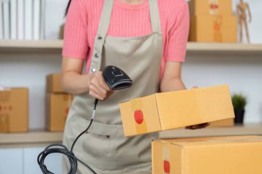 Genç bir kadın envanteri kontrol etmek için barkod tarayıcısı kullanıyor. Küçük işletmelerinde verimlilik ve organizasyon gösteriyor..