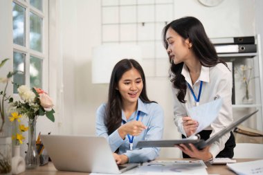 İki bayan meslektaşım proje belgelerini ve verileri parlak bir ofisteki bir laptopta incelerken bir tartışmaya giriştiler..