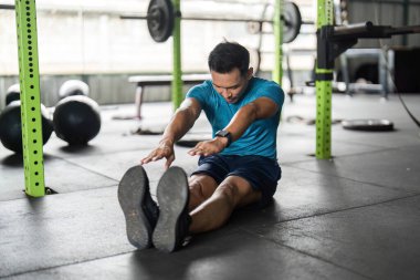 Bir fitness meraklısı oturup ayak parmaklarını esnetme, esnekliği artırma ve genel sağlık hizmetlerini teşvik etme pratiği yapar..