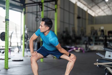 Formda bir adam spor salonunda çömelir, kondisyona odaklanır ve vücut gücünü arttırır..