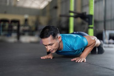 Modern bir spor salonunda şınav çeken kendini adamış bir adam, dayanıklılık eğitimi ve fitness bağlılığı sergiliyor.