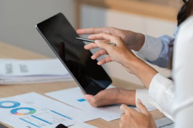 Mali veri ve raporları analiz etmek için bir tablet kullanan iki meslektaş, takım çalışmasını ve verimliliğini artırıyor.