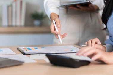 Çağdaş ofis ortamında bilgi ve stratejileri tartışan iki kadın, veri analizinde işbirliği yapmaktadır..