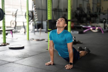 Spor salonunda kobra pozu veren bir adam, esneklik ve uygunluk ve sağlığa olan bağlılığını gösteriyor..