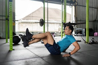 Erkek bir sporcu spor salonundaki güç ve zindelik için karın kaslarını hedef alarak bisiklet çatırdatıyor..