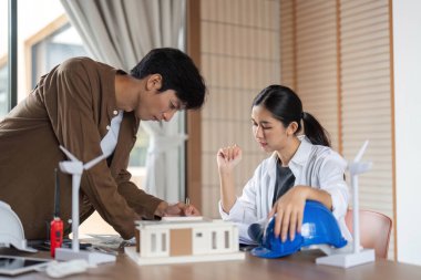 Bir erkek ve kadın mimar, sürdürülebilir mimari için yenilikçi tasarımlar üzerinde birlikte çalışarak ESG ilkelerine odaklanırlar..