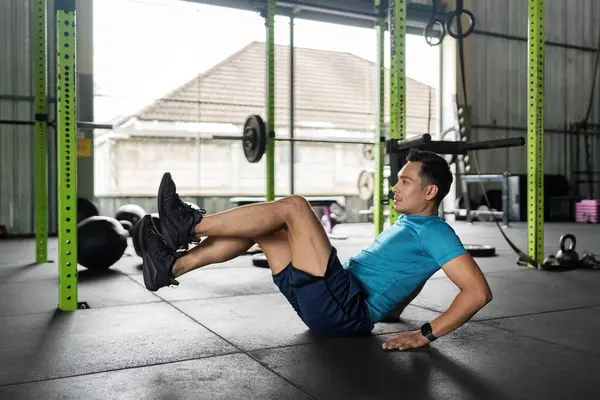 Erkek bir sporcu spor salonundaki güç ve zindelik için karın kaslarını hedef alarak bisiklet çatırdatıyor..
