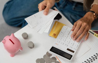 Faturaları inceleyen ve harcamaları yönetmek için hesap makinesi kullanan biri. Finansal sorumluluk ve bütçeye vurgu.
