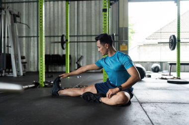 Erkek bir sporcu kaslarını bir fitness merkezinde oturarak bükerek esnek ve sağlıklı olmayı teşvik eder..