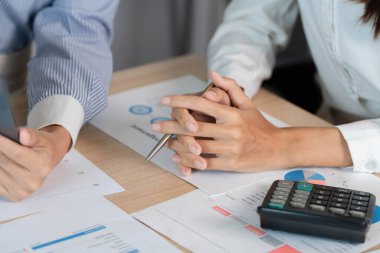 İki iş adamı, hesap makinesi ve belgelerle raporları ve verileri analiz ederek finansal bir tartışmaya giriştiler..