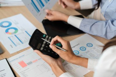 Finansal ölçümleri hesap makinesiyle hesaplayan, kavrayış ve stratejileri tartışan iş adamları.
