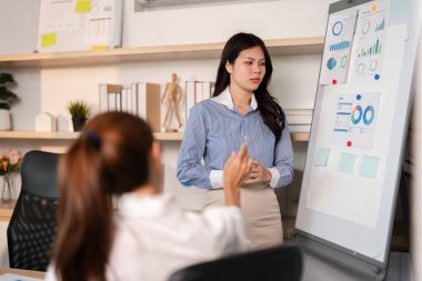 Modern bir ofiste, bir kadın veri içgörülerini düşünceli bir ifadeyle sunar, meslektaşını anlamlı bir tartışmaya dahil eder..