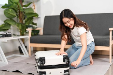 Bavulunu rahat bir salonda düzenleyen mutlu bir gezgin seyahat hazırlıklarının neşesini somutlaştırıyor..