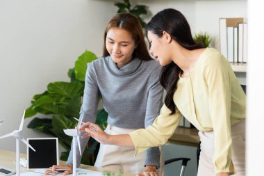 ESG stratejileri üzerinde işbirliği yapan profesyoneller, modern bir ofiste rüzgar enerjisi çözümleri ve sürdürülebilirlik girişimlerine odaklanıyorlar..