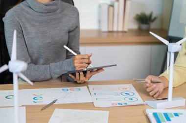 ESG stratejilerini tartışan, grafikleri analiz eden ve modern ofis ortamında sürdürülebilirliğe odaklanan iki iş adamı..