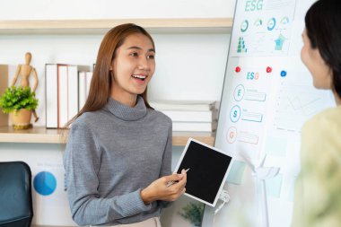 Ekibine ESG ölçüm ve stratejilerini hevesle sunan genç bir kadın, sürdürülebilirliği vurguluyor.
